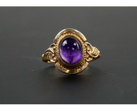 A cabochon amethyst ring with scroll decorated shoulders, 9 ct ring size 0 .    