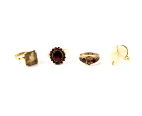 Four rings, one set with rectangular step cut Smokey quartz, ring size K, another white hard stone carved face, size L, both 