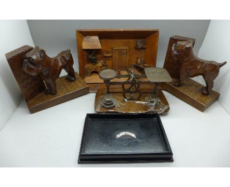 A pair of carved wooden dog bookends, a large page turner, a carved diorama, postal scales and a silver mounted ebony tray