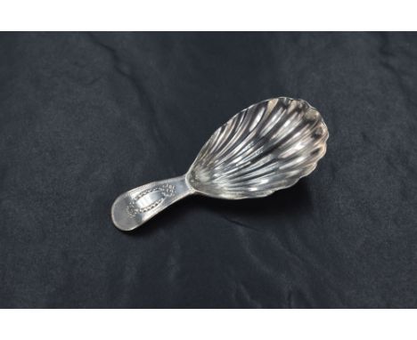 A George III silver caddy spoon, of traditional form having scalloped bowl with bright cut engraving to the terminal, rubbed 