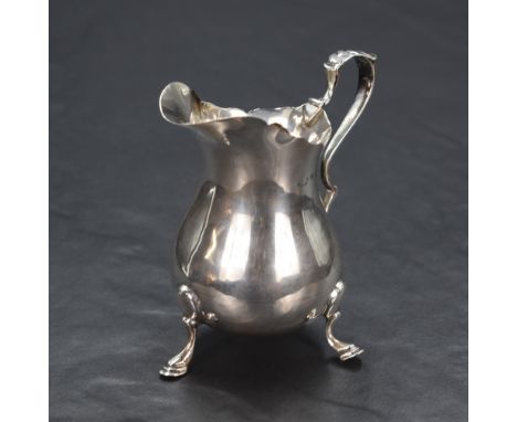 A George V silver cream jug, having a Chippendale style rim with a narrow spout opposed by a scroll handle, engraved with lio