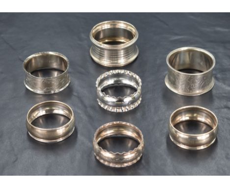 A group of seven early 20th century silver napkin rings, of various size and design including crimped rims, decorative engrav
