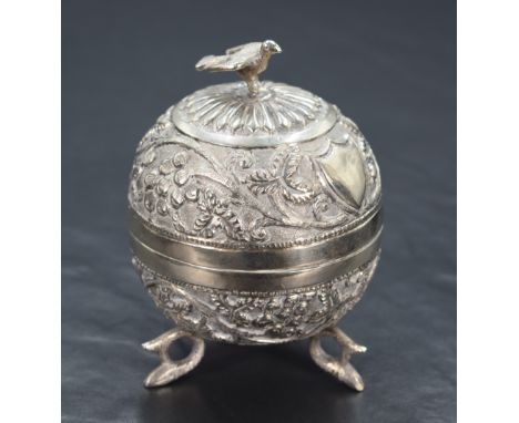 An Eastern white metal trinket box, of circular form having a bird form finial with embossed floral decoration and vacant shi