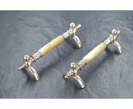A pair of mother-of-pearl and white metal knife rests, of traditional form having central mother-of-pearl bars, raised on whi