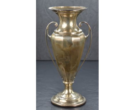 A George V silver vase, having a flared rim and canted body with scroll handles, raised on a circular step moulded foot, mark