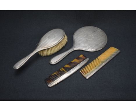 A George V silver mounted vanity set, comprising a hair brush, comb and mirror having engine turned decoration with central c