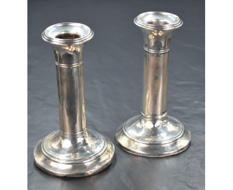 A pair of Edwardian silver candlesticks, having step moulded sconces and moulding to the stems, raised on circular step mould