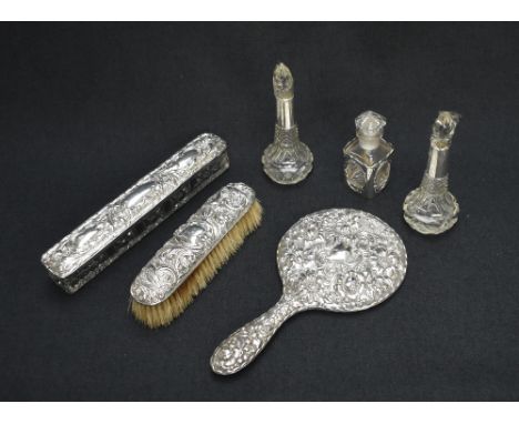 An Edwardian silver mounted mirror having embossed floral and scroll decoration, along with a silver mounted clothes brush, h