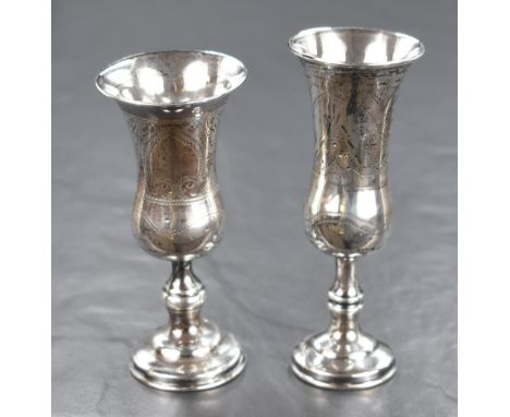 Two Edwardian silver Kiddush cups, both of traditional form having decorative engraving, raised on knopped stems and circular