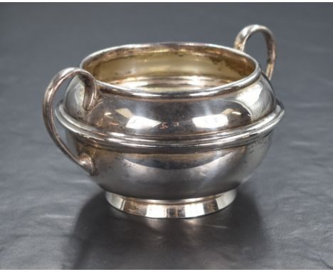 An early 20th century silver sugar bowl, of rounded form having two C scroll handles and step moulded detail to the body, rai