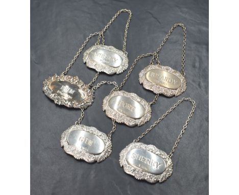 A group of six silver decanter labels, comprising Whisky, Gin, Rum, Brandy, Sherry and Port, all having decorative embossed s