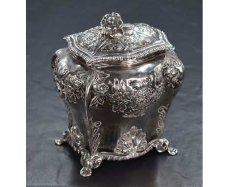 A late Victorian silver tea canister, of bulbous rectangular form, having a flower form finial, gadrooned rim and embossed fl