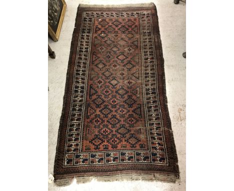 A Belouch tribal rug, the central panel set with repeating lozenge medallions on a dark red ground within a stepped red, blue