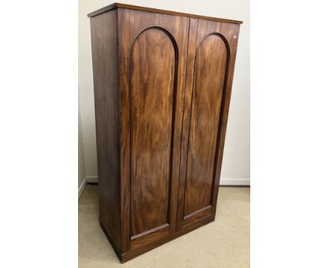 A Victorian mahogany wardrobe, the replacement shallow cornice over two arched panelled doors enclosing a shelf, hanging spac