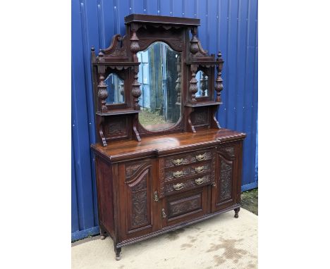 A late Victorian carved walnut side board with mirrored super structure over three central drawers and cupboard door flanked 