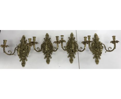 A set of four 20th Century brass twin light wall candle sconces in the Baroque style with Bacchus mask and gryphon and scroll