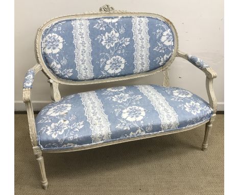 A circa 1900 cream painted framed and carved two seat salon sofa in the Louis XVI taste with upholstered back, elbow pads and