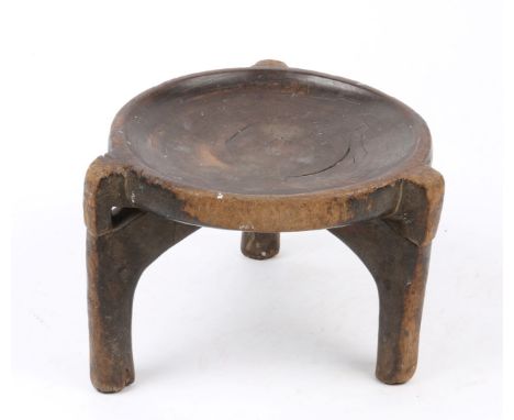 AN ANTIQUE AFRICAN CIRCULAR TRIBAL STOOL on stylised elephant trunk supports, 24cm diameter