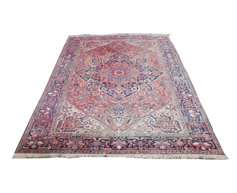 A LARGE OLD PERSIAN CARPET with all over foliate decoration within a wide blue ground border