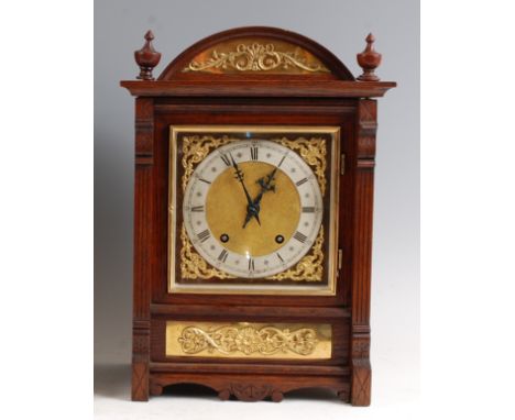 A circa 1900 oak cased mantel clock, the square brass dial having silvered chapter ring, twin winding holes for a Winterhalde