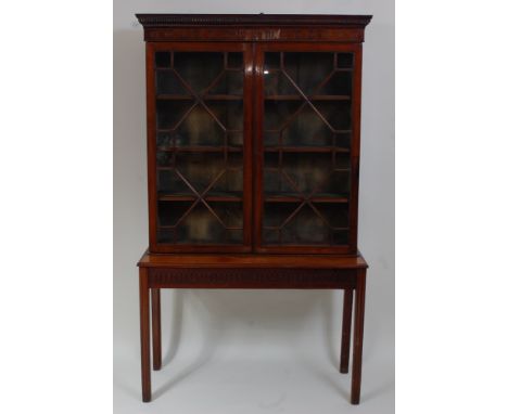 *An Edwardian mahogany bookcase on stand, the upper section having adjustable shelves enclosed by astragal glazed doors, the 