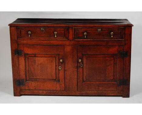 An early 18th century joined oak dresser base, the top having a moulded edge over twin frieze drawers and panelled doors on i