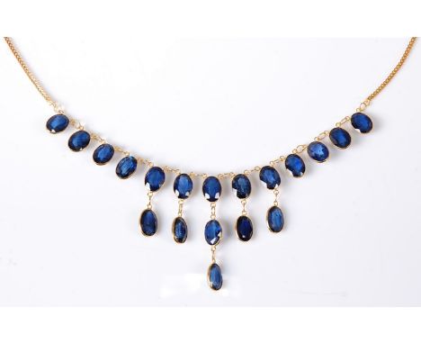 A '21k' sapphire fringe necklace, the oval spectacle set sapphires, each approx. 6.5mm long, (19 in total), longest drop 26mm