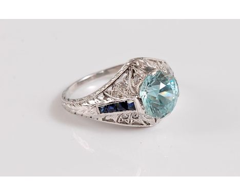 A platinum, zircon, sapphire and diamond ring, the central pale blue zircon, approx. 8mm diameter, with a channel to either s