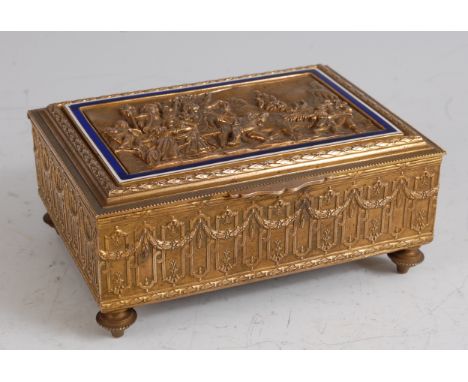 A late 19th century brass music box, the hinged cover cast with a scene of merry-making and livestock amidst a landscape, all