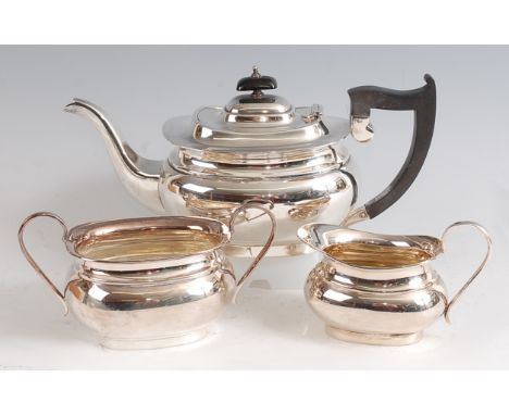 A Georgian style silver three-piece tea set, comprising teapot, twin handled sugar and cream, each of undecorated oval bombe 