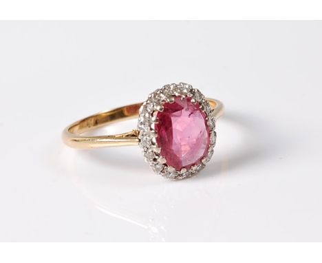 An 18ct pink sapphire and diamond ring, the oval pale raspberry pink sapphire, approx. 9.1 x 7.5 x 2.5mm, surrounded by small