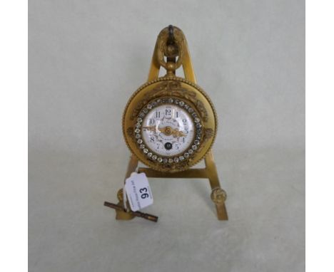 An early 20th century gilt circular clock, mounted to a brass easel stand, the painted enamel dial bearing Arabic numerals an