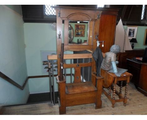 An early 20th century oak mirror back hall stand, the lift flap central seat flanked by twin stick stands, 194cm x 88cm.