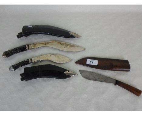 Two leather cased kukri knives, together with a further wooden cased knife.
