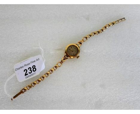 A lady's 9ct gold cased wristwatch (lacking glass), the dial bearing Arabic and baton numerals, to a 9ct gold bracelet.   Con