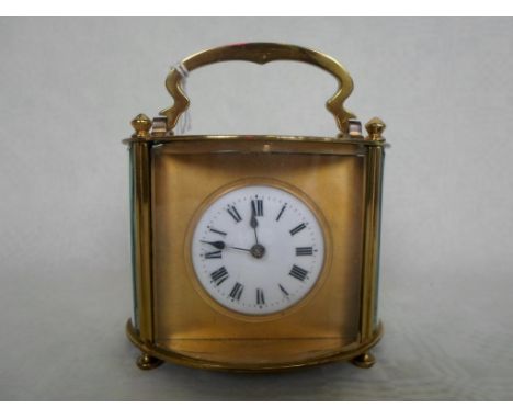 A French gilt brass carriage clock of oval form, having five bevel edged glass panels, the circular enamel dial bearing Roman