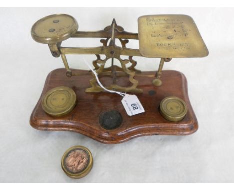 A set of early 20th century brass postal scales and weights, mounted to wooden plinth.