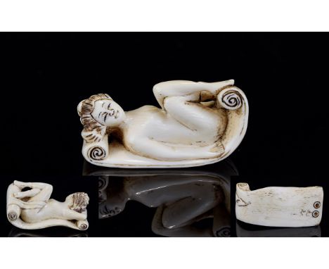 Antique Ivory Erotic Netsuke Finely carved in the form of a recumbent nude female figure lying on a shikibuton, her knees dra