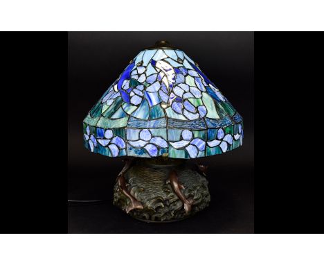 Tiffany Style Table Lamp with squat heavy solid base surmounted by dolphin figures. The blue and green lamp shade also decora