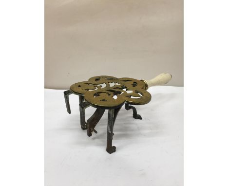 AN UNUSUAL VICTORIAN BRASS TRIVET WITH A CERAMIC HANDLE 