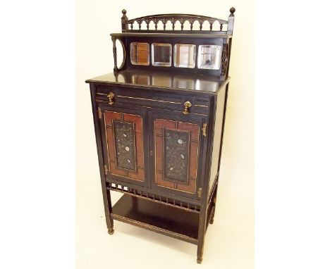 A Victorian Aesthetic movement ebonised cabinet with mirrored shelf over fitted drawer and two floral painted doors, spindle 