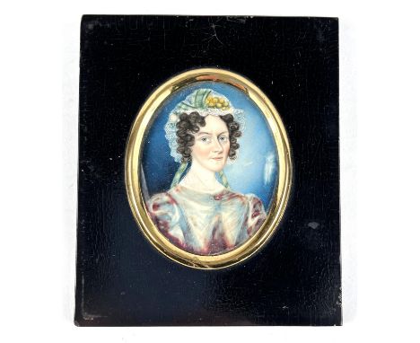 An early 19th century 1/2 length miniature portrait of a woman with a floral lace bonnet on ivory panel, in ebonised &amp; gi