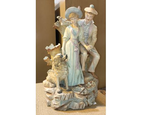 A 19th century, coloured bisque courting couple with a dog, standing on rocks. height 43cm 