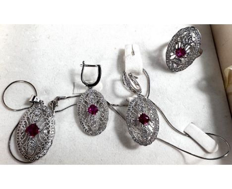 A suite of white metal jewellery stamped 925, necklace, earrings, ring, set with ruby coloured central stone surrounded by cl
