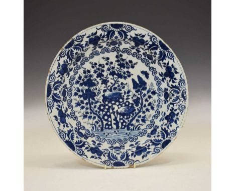 18th century Delftware shallow dish, decorated with trees and rock work within floral borders, unmarked, 38.5cm diameter