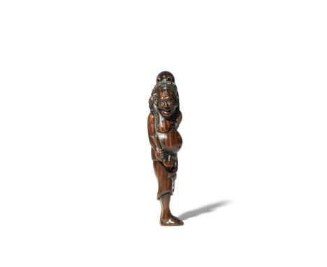 A JAPANESE WOOD NETSUKE MEIJI 1868-1912 Depicting a tall standing man with a large octopus on his head, holding a pipe in his