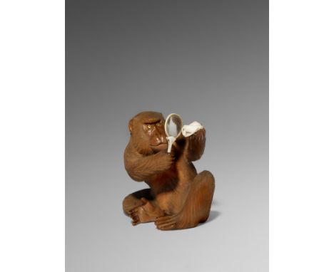 λ A JAPANESE BOXWOOD OKIMONO OF A MONKEY MEIJI 1868-1912 The primate depicted seated and examining a small hermit crab throug