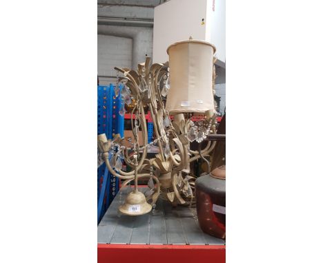 A chandelier light fitting with glass droplets, and a table lamp on a brass base 