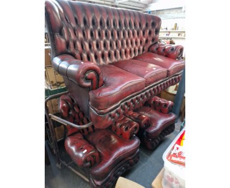 An oxblood red leather Chesterfield sofa and two matching armchairs. 