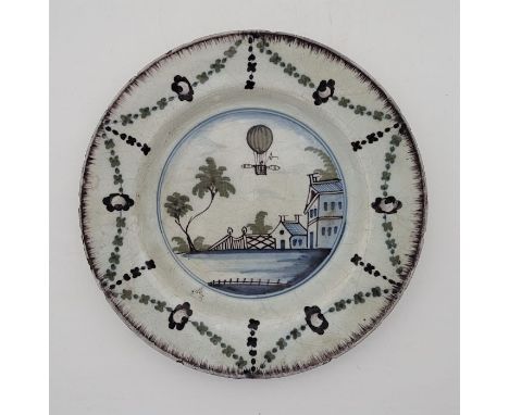 An 18th century English Defltware plate, the rim with manganese glaze, painted in colours, the reserve painted with balloon, 